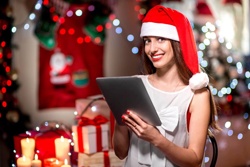Woman holding an iPad wearing a Christmas hat. 
