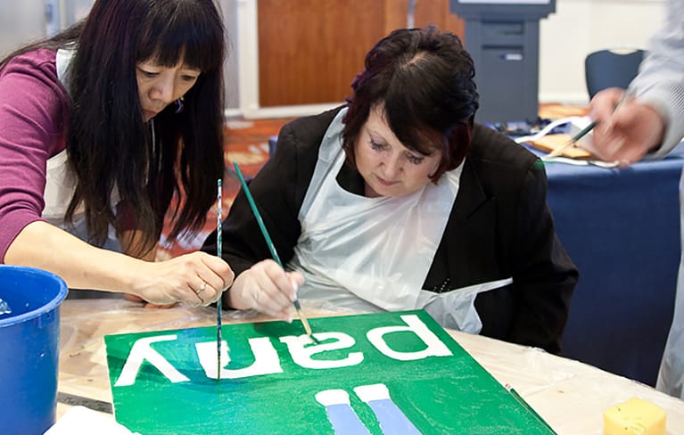 Two people painting a sign